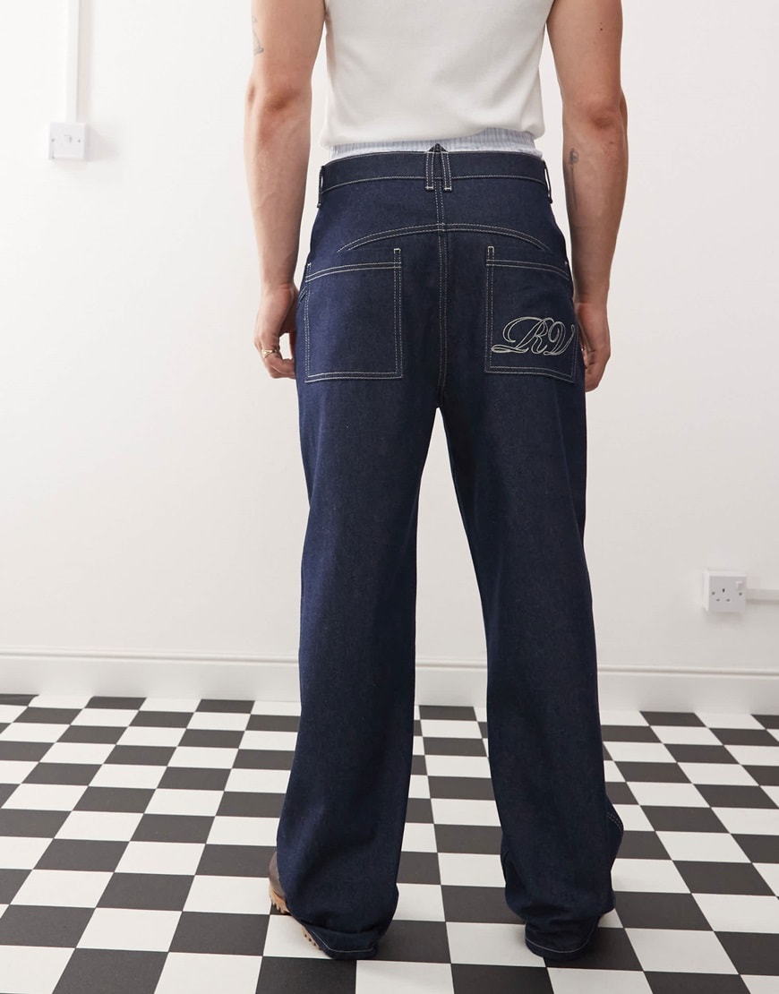 Model wearing dark blue baggy jeans with a letter on the back pocket