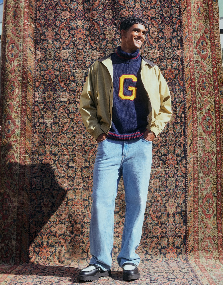 Model wearing beige jacket and navy jumper with yellow G