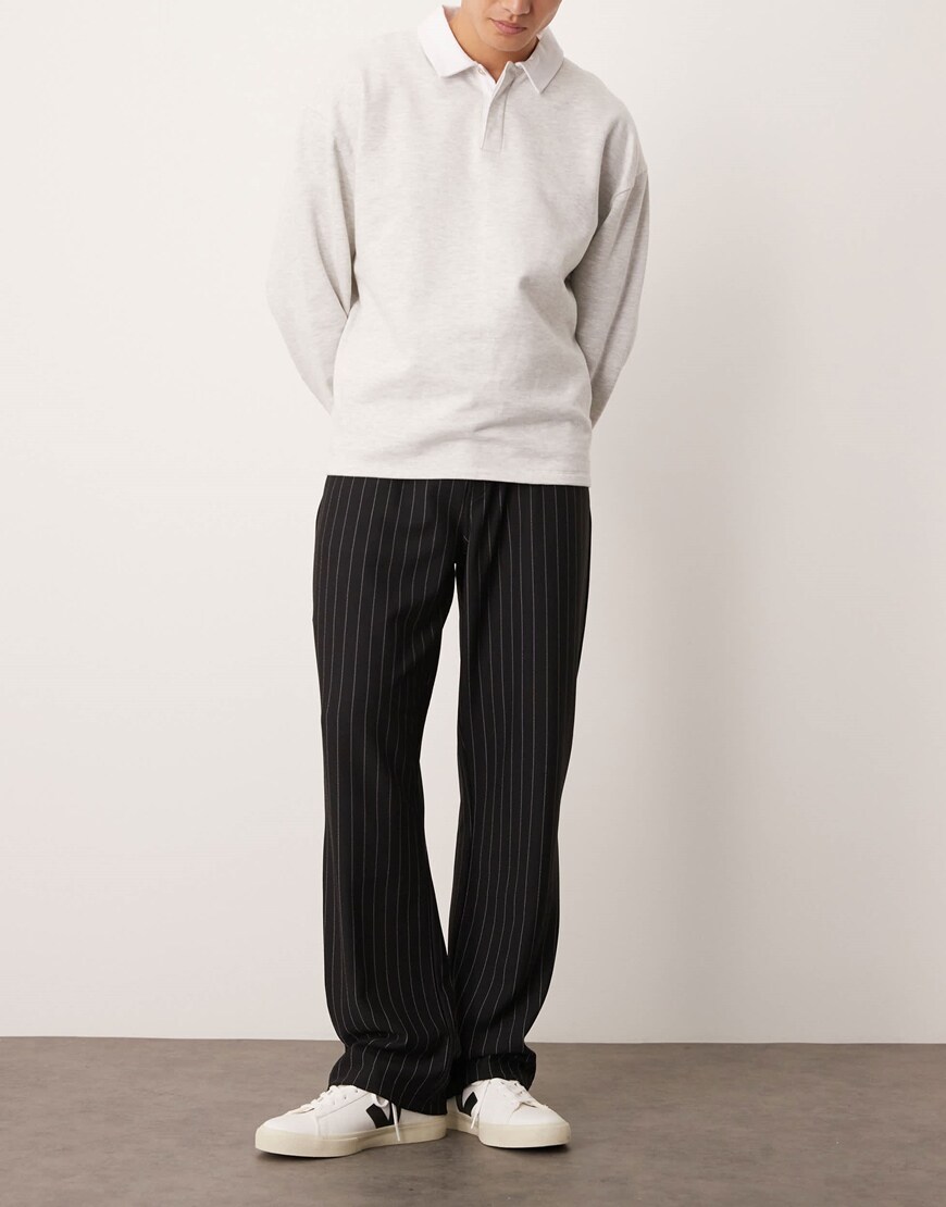 Model in grey polo shirt and baggy trousers in black pinstripe