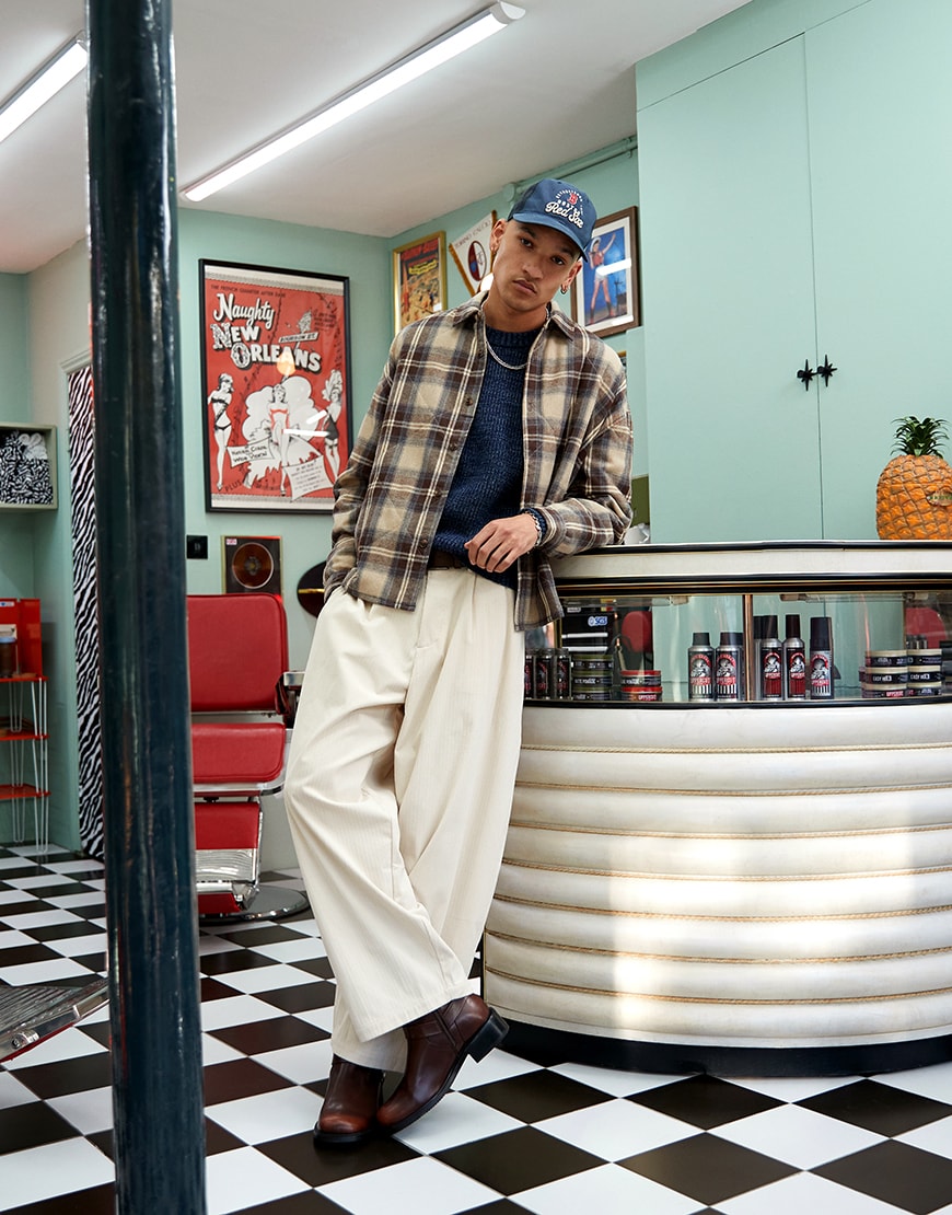 A man wearing a checked shirt, a knitted top and cream pants | ASOS Style Feed