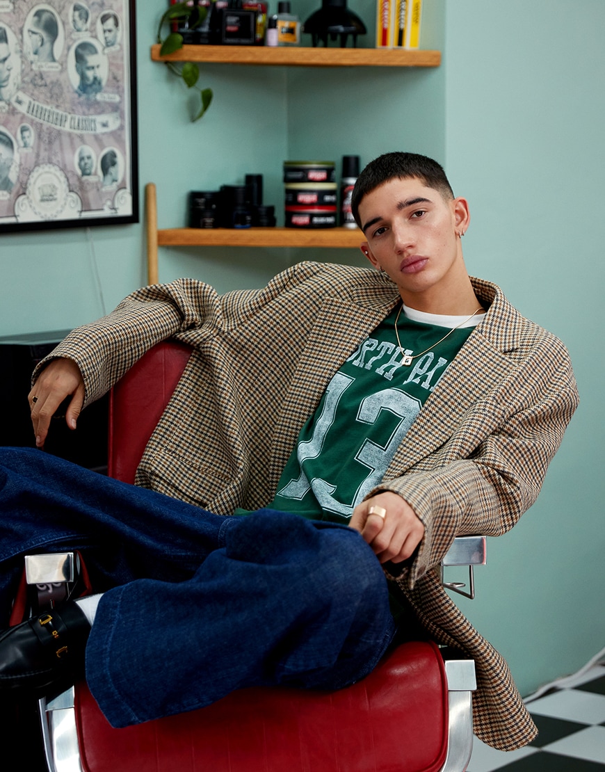 A man wearing a checked blazer with a green top and blue jeans | ASOS Style Feed