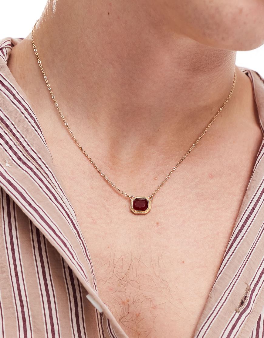 Model wearing gold necklace with red gemstone