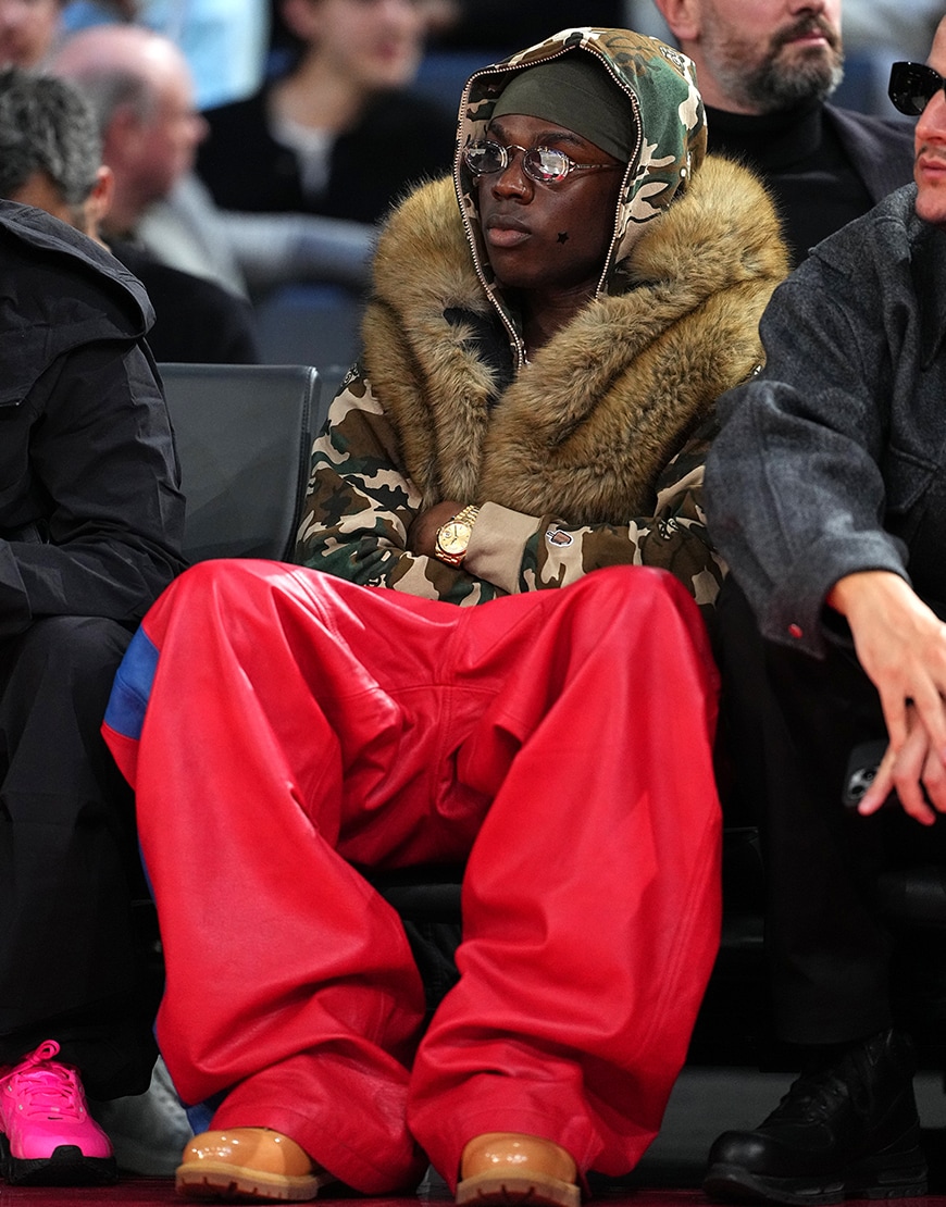 Rema wearing a camo hoodie and red trousers