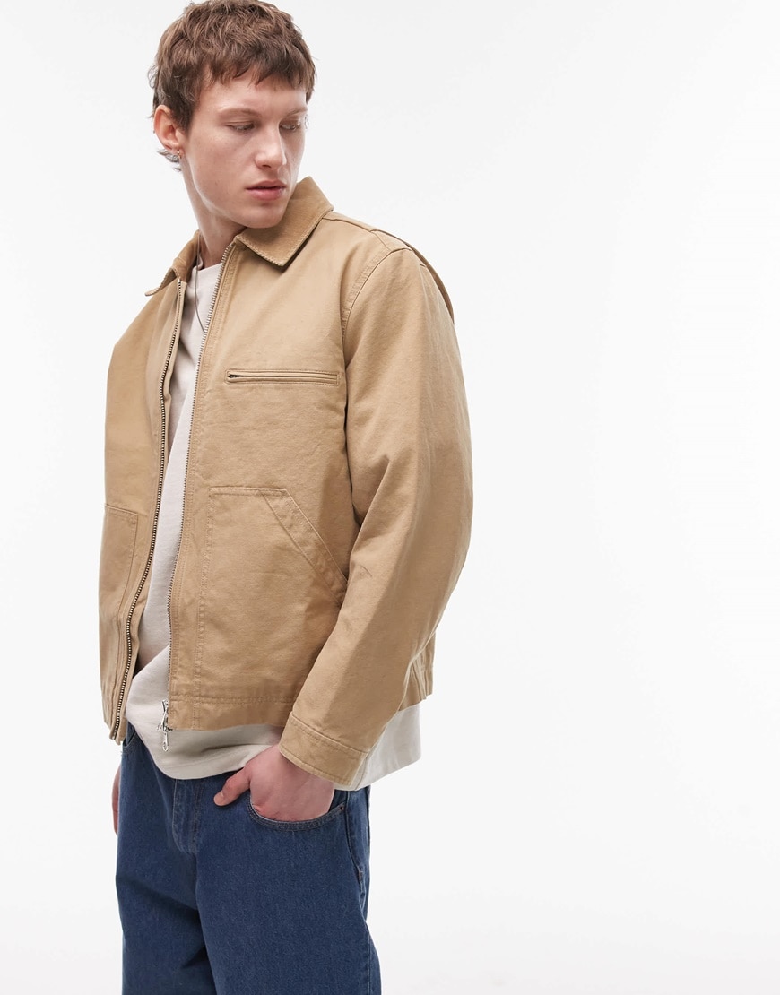 Model wearing tan coat and blue jeans