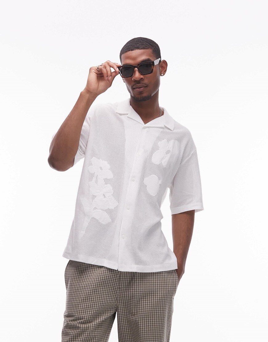 A model wearing a white embroidered floral shirt