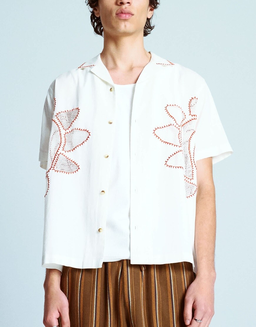 A model wearing a white embroidered shirt