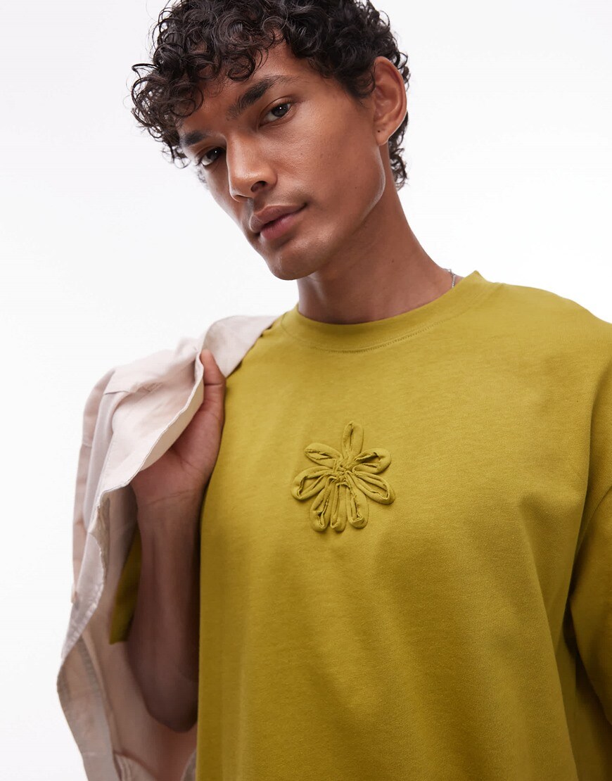 A model wearing a mustard t-shirt with a flower embroidery