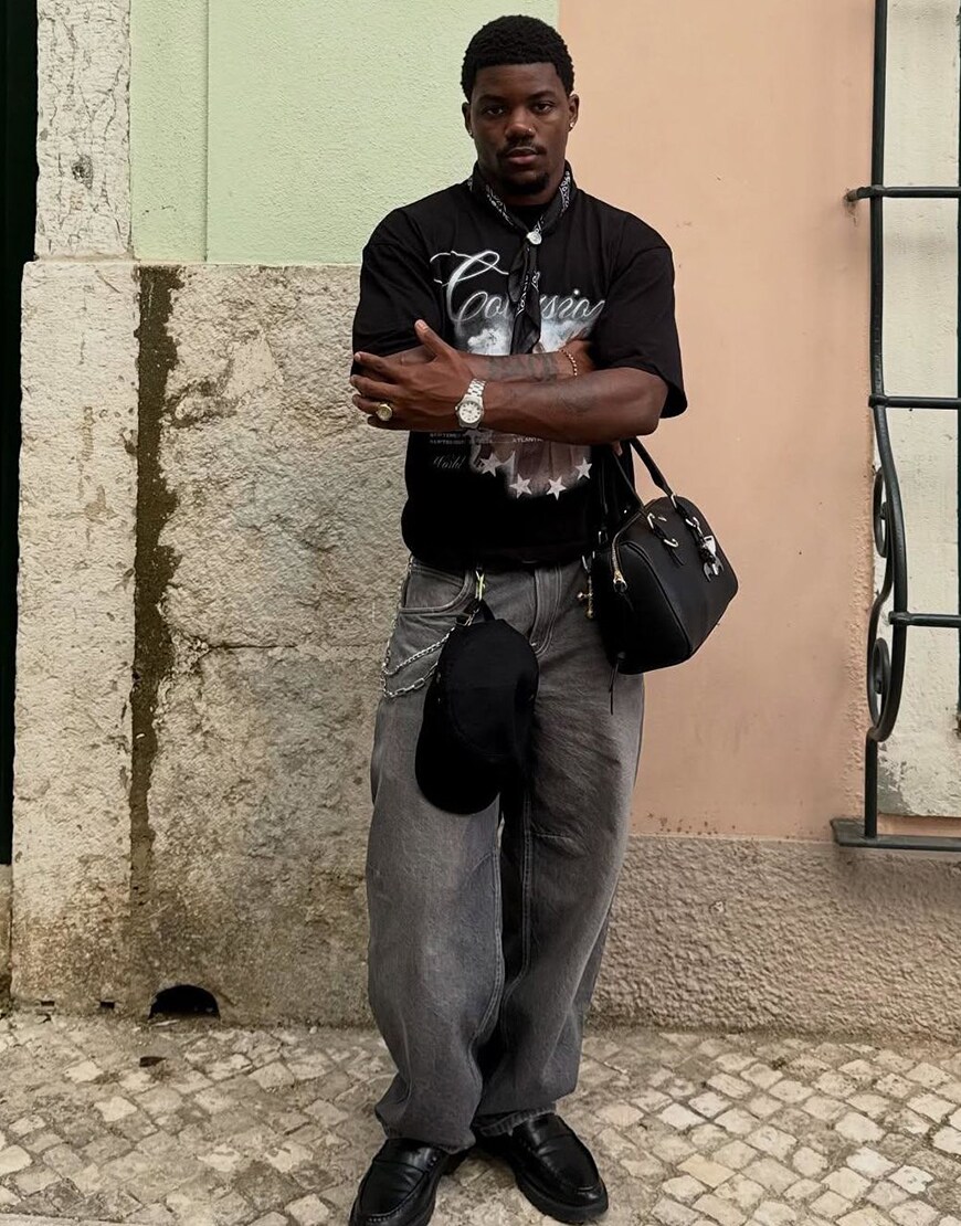 Man wearing grey baggy jeans and a black graphic t-shirt
