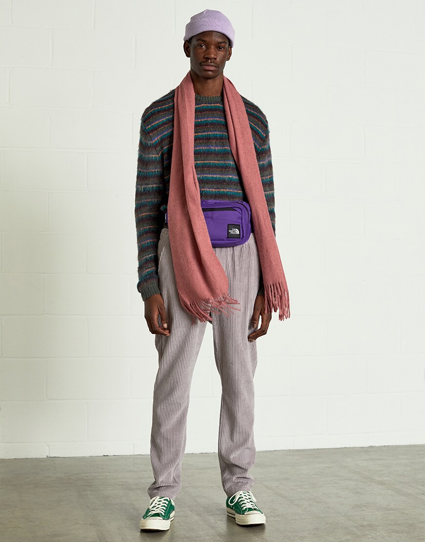 A model wearing a lilac hat, a striped jumper, cord trousers, a pink scarf and green Converse trainers | ASOS Style Feed