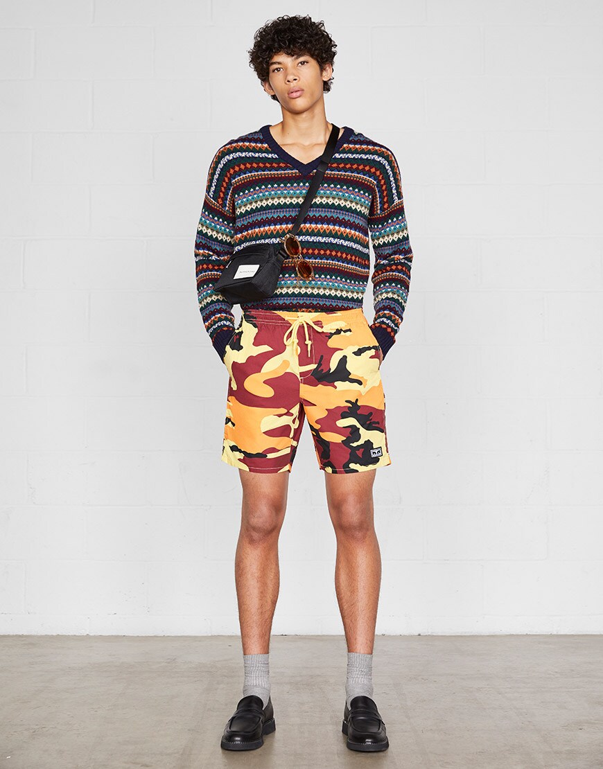 A model wearing a knitted jumper, retro shades, a cross-body bag, camouflage swim shorts and loafers | ASOS Style Feed