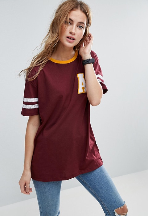 Model wearing maroon ASOS T-Shirt with college badges and blue jeans | ASOS Fashion & Beauty Feed