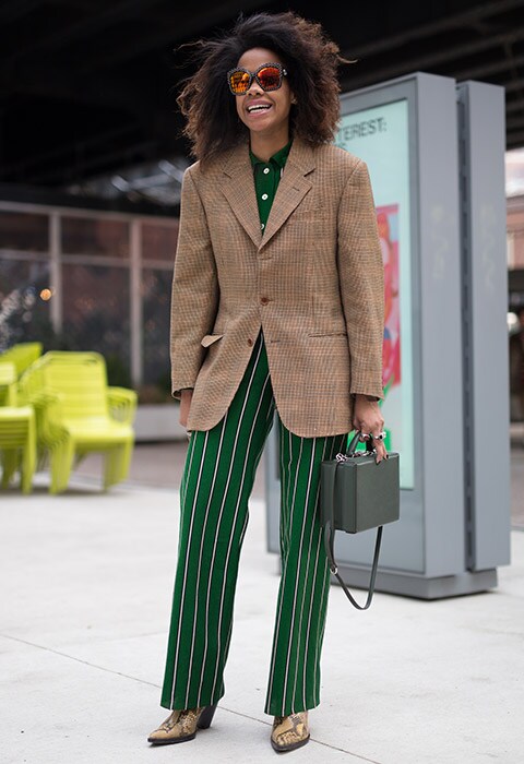 Jan-Michael Quammie attending fashion week wearing a tweed blazer with stripy green trousers and snakeskin boots.