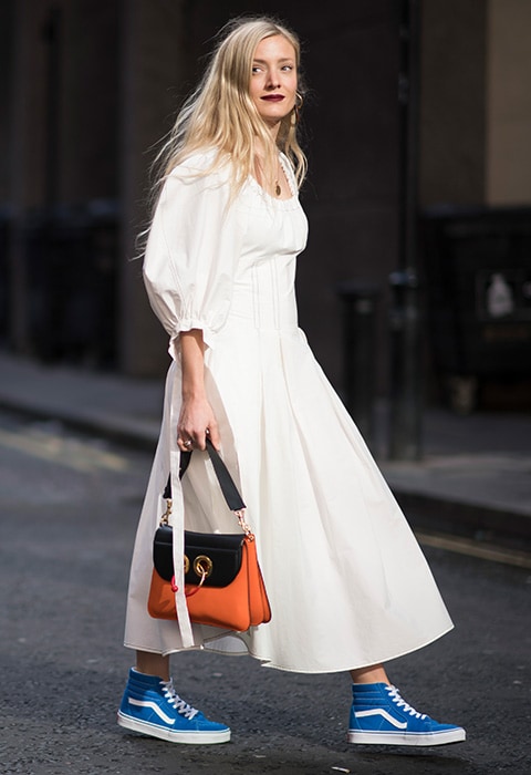 Kate Foley wearing a white midi dress with blue Vans trainers and a colour-block bag.