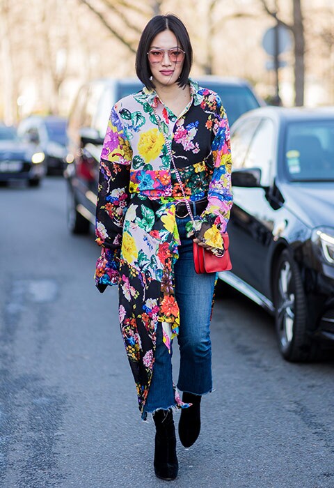 Tifffany Hsu attending fashion week wearing a floral midi dress, tucked into ankle-grazing jeans, complete with tinted sunglasses.