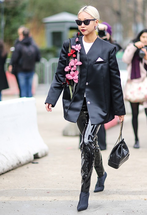 Vanessa Hong attending fashion week wearing a boxy satin blazer with PVC trousers and sock boots.