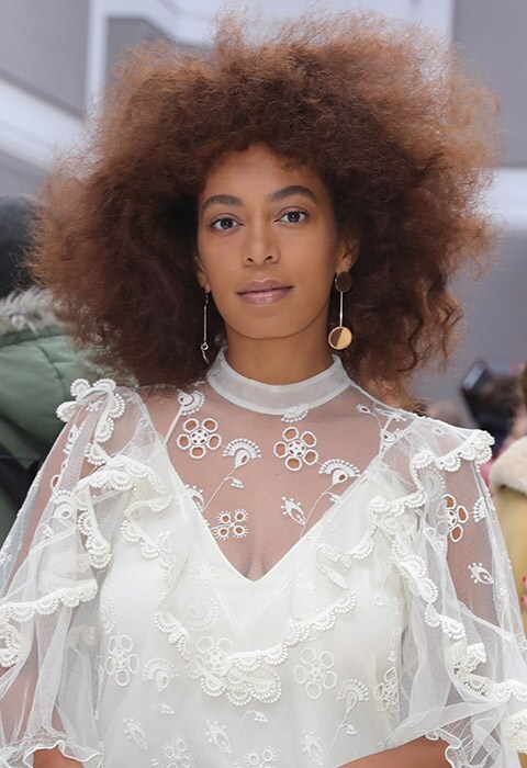 Solange Knowles wearing a white embroidered dress and gold earrings