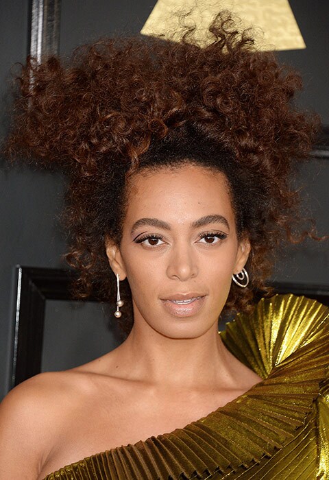Solange Knowles wearing a gold dress and asymmetric earrings