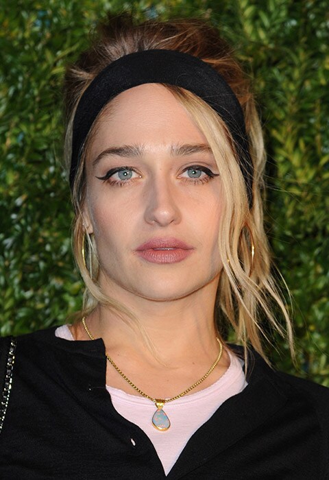 Jemima Kirke wearing hair up in a beehive with black alice band and gold hoop earrings