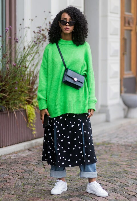 Street style look with oversized green knit, cross body bag, spliced midi skirt and straight leg jeans