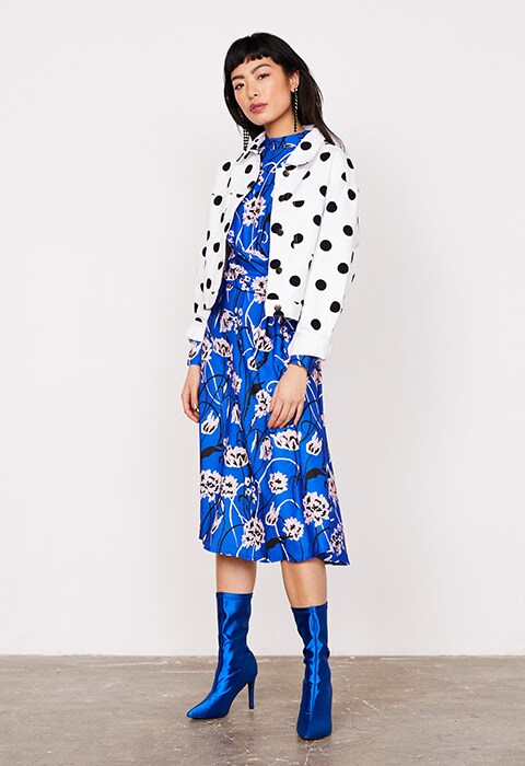 Model wearing a blue floral dress and polka dot jacket