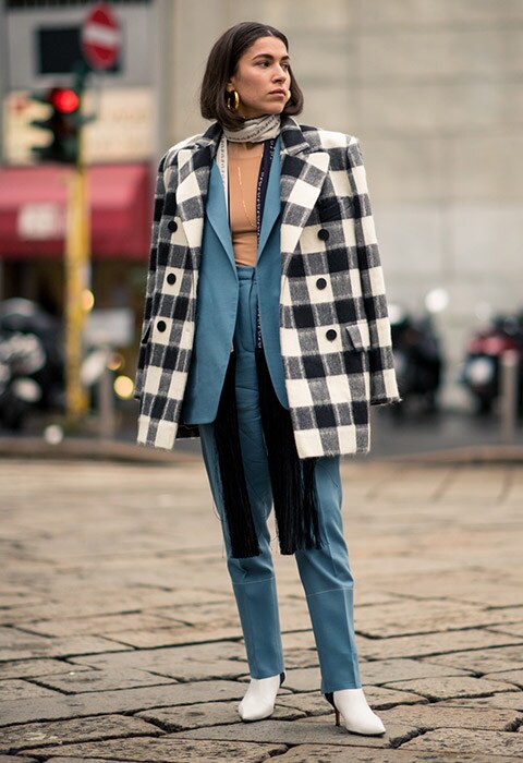 Blogueuse mode street style pendant le mois de la Fashion Week AH18 portant un costume bleu canard et une veste à carreaux