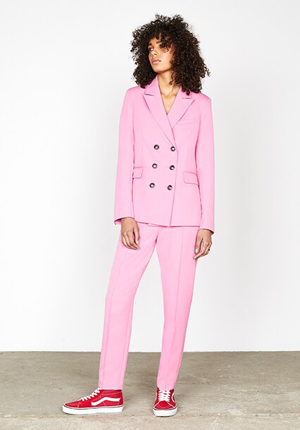 Model wearing a pink blazer with pink trousers