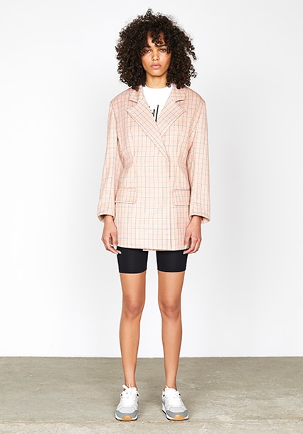 Model wearing a peach check blazer over gym shorts, available at ASOS