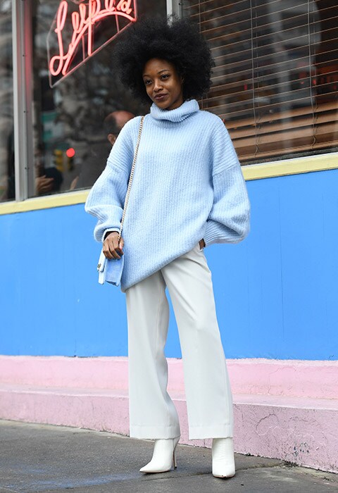 Model wearing a blue jumper and white wide-leg trousers in New York