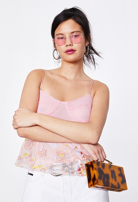 Model wearing pink sunnies and a pink cami