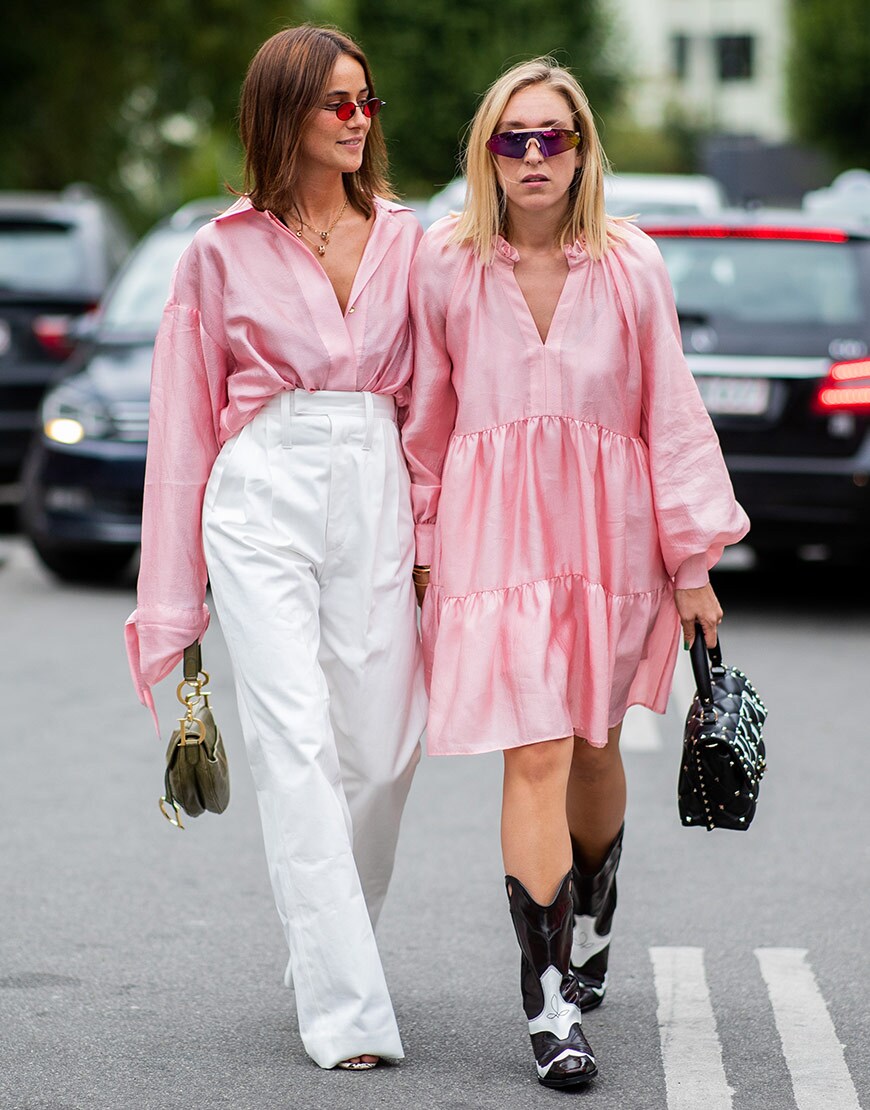 street style portant une chemise rose sur un pantalon blanc et une robe à volants rose fashion week copenhague