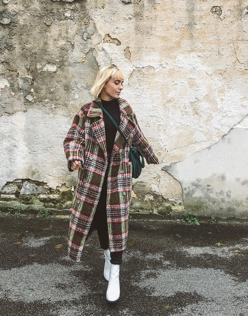 ASOS Astrid porte un total look black avec des bottines blanches et un manteau à carreaux