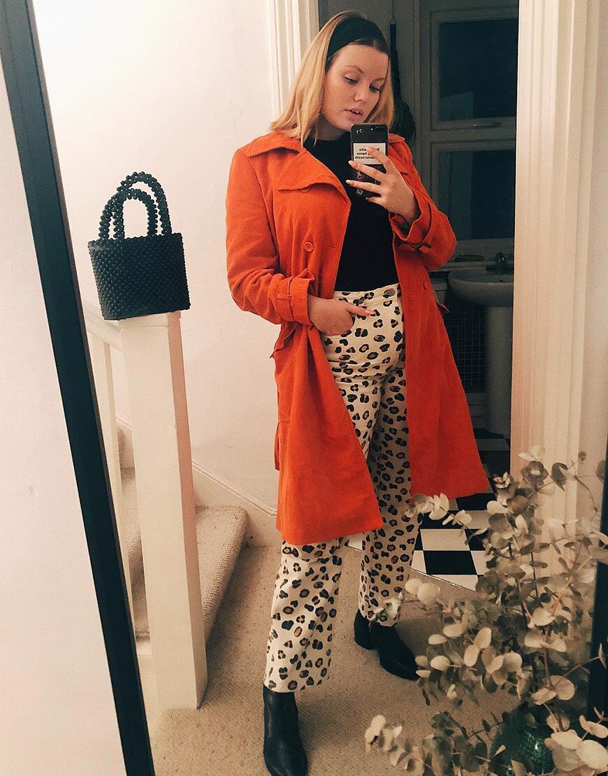 ASOS Lotte porte un pantalon imprimé léopard avec un trench orange et un sac en perles
