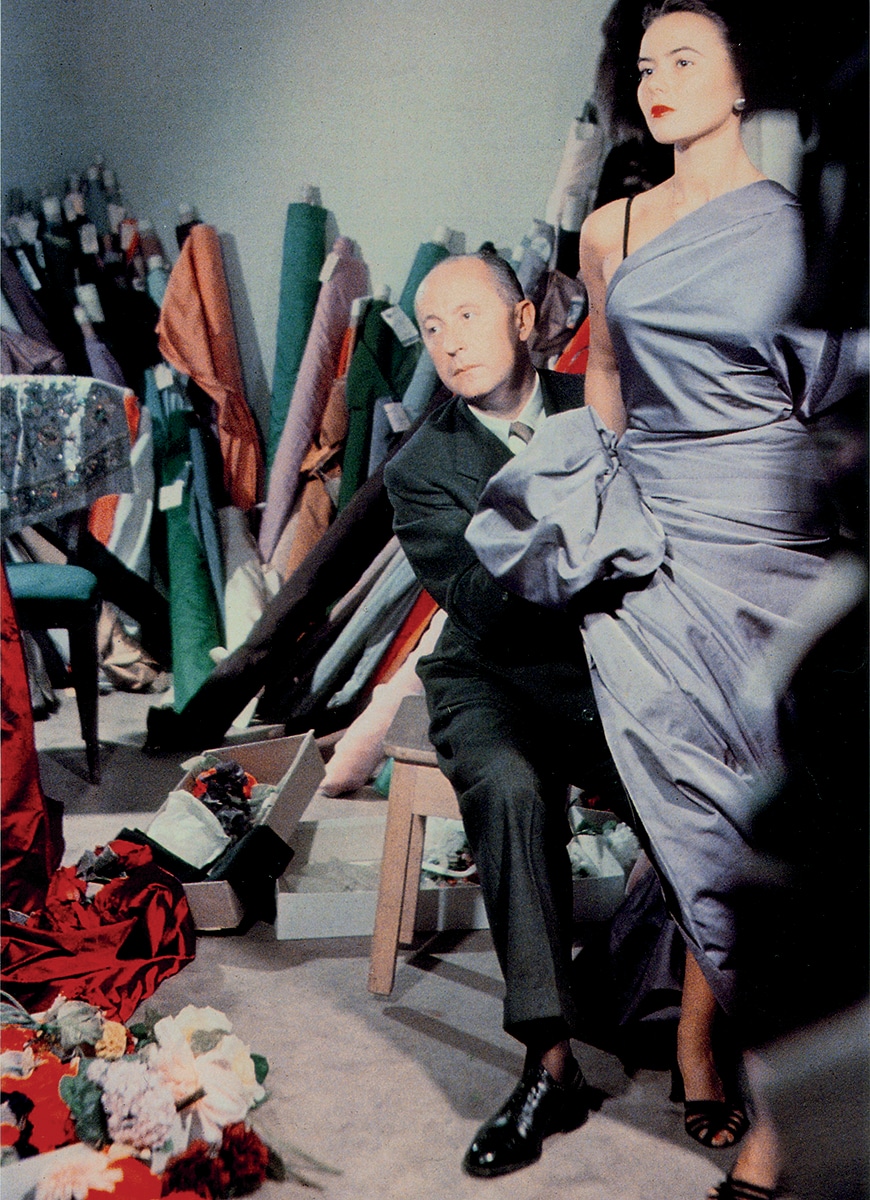 A photo of Christian Dior adjusting a model's dress