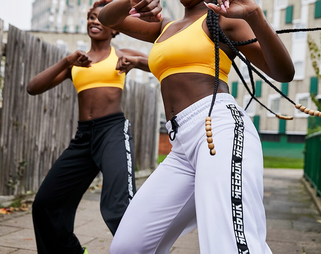 A picture of two women dancing in Reebok sportswear on the streets of London. Available on ASOS.