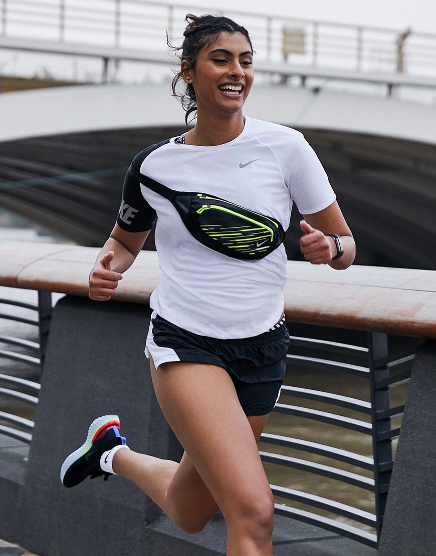A picture of a woman running in a T-shirt and shorts by Nike Running. Available on ASOS.