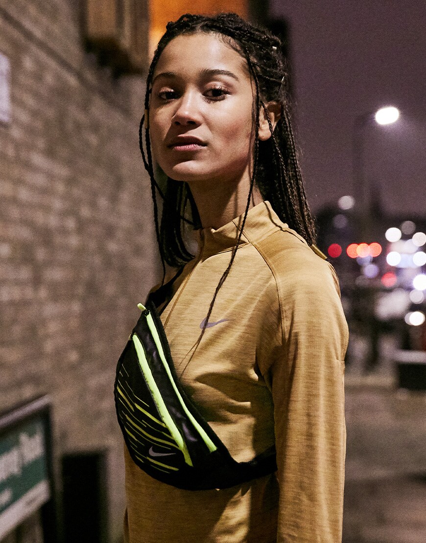 A picture of a woman wearing a Nike Running top and bum bag. Available at ASOS.
