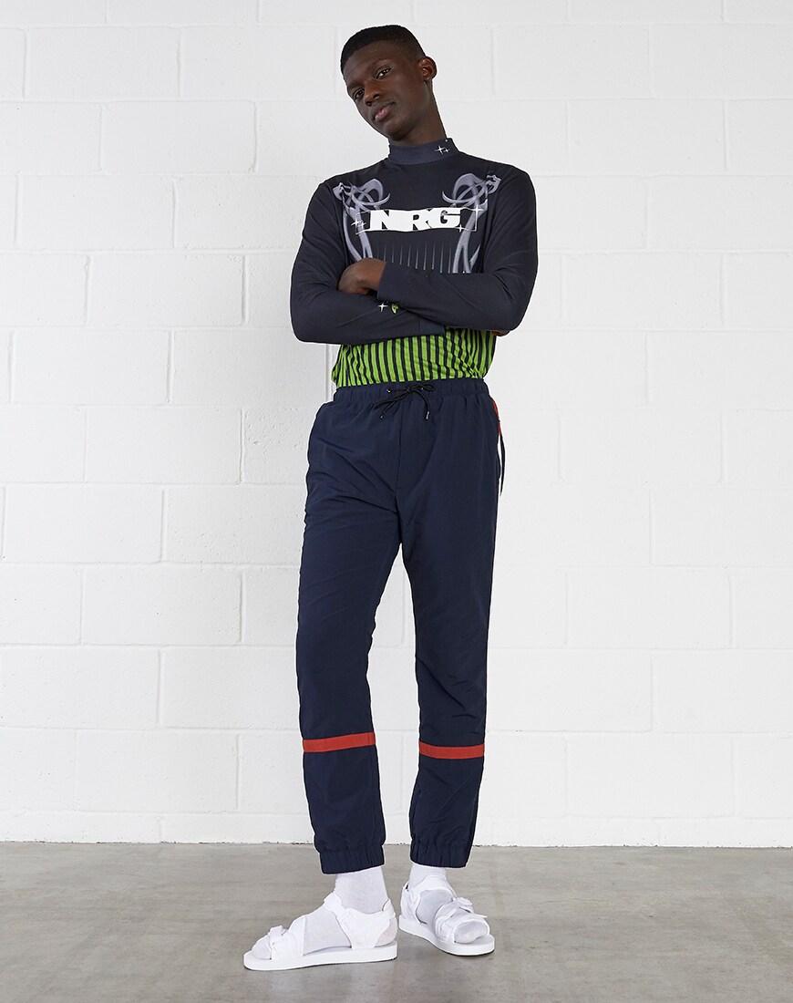A model in a graphic top, navy track pants and white sandals | ASOS Style Feed
