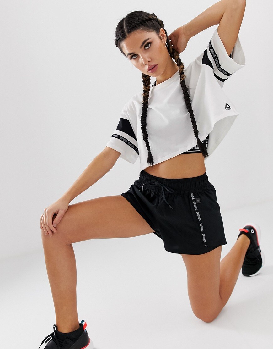 A picture of a woman wearing a black and white, cropped training top by Reebok