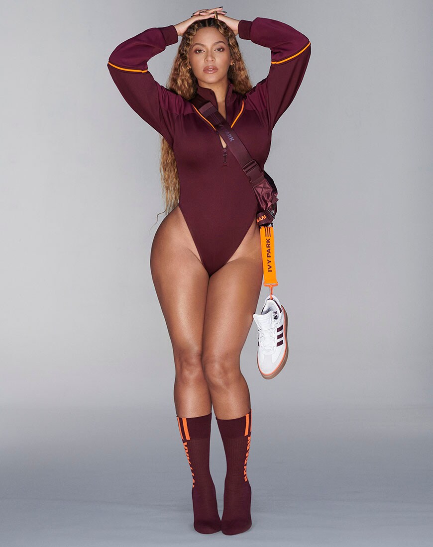 Beyonce with arms up wearing a burgundy bodysuit