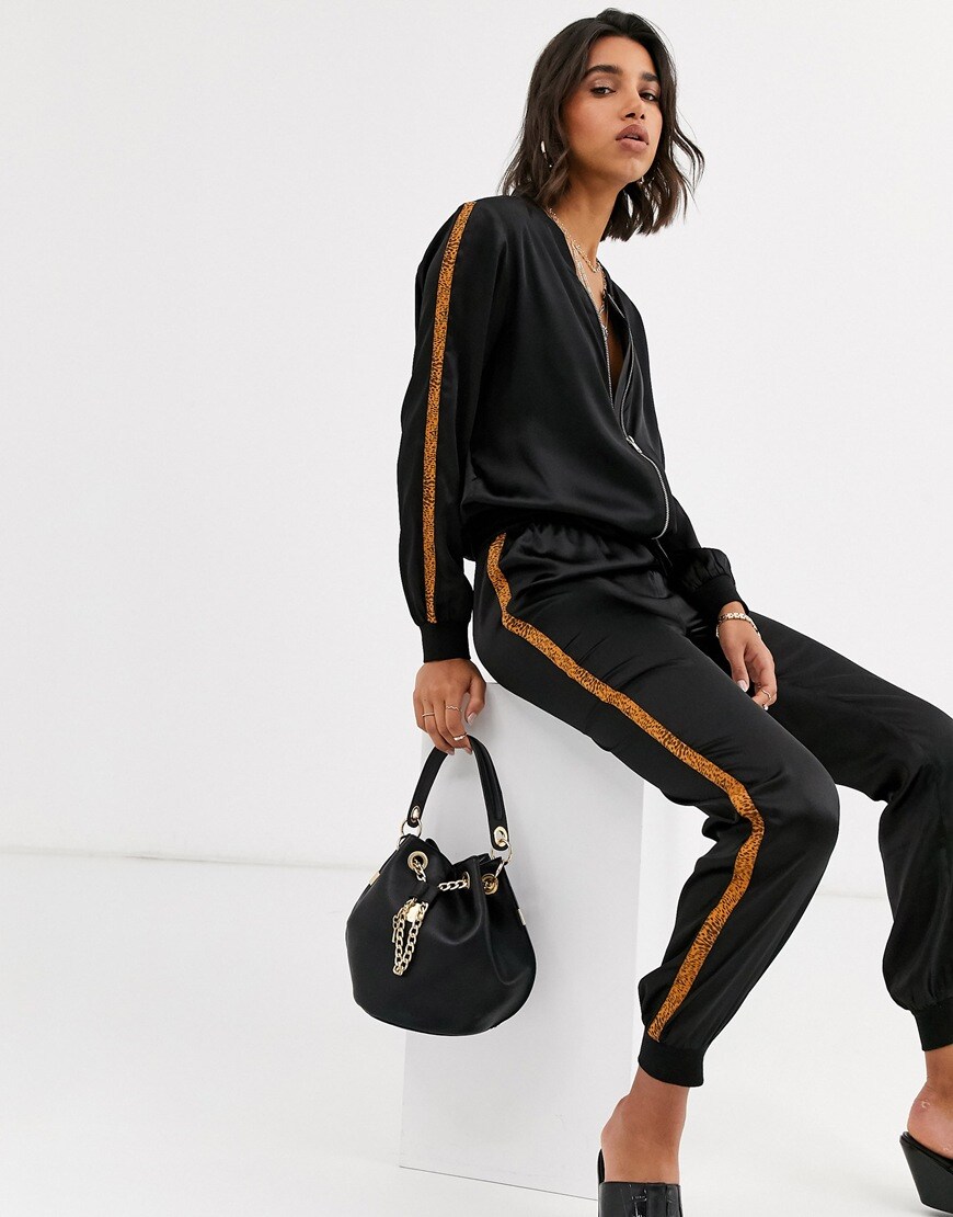 A picture of a model wearing a pair of ASOS DESIGN satin-style joggers and a matching hoodie. Available at ASOS.