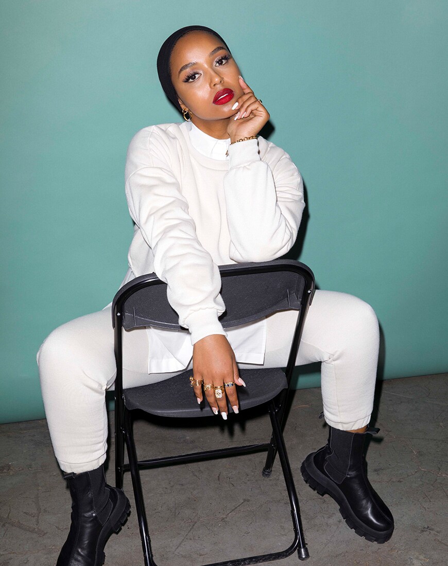 A picture of modest-fashion influencer and beauty blogger Shahd Batal. Shad wears a white sweatshirt and joggers co-ord with chunky boots. Available at ASOS.