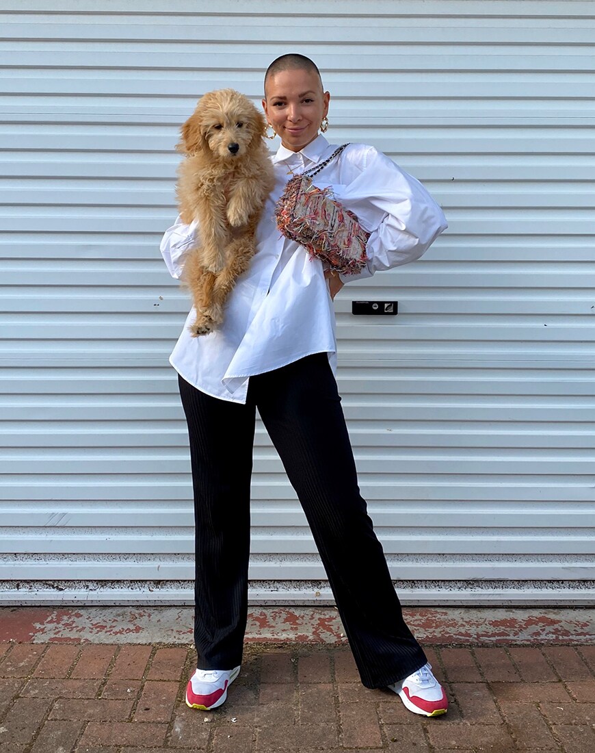 Beth in a white shirt and black flared trousers while holding a puppy | ASOS Style Feed