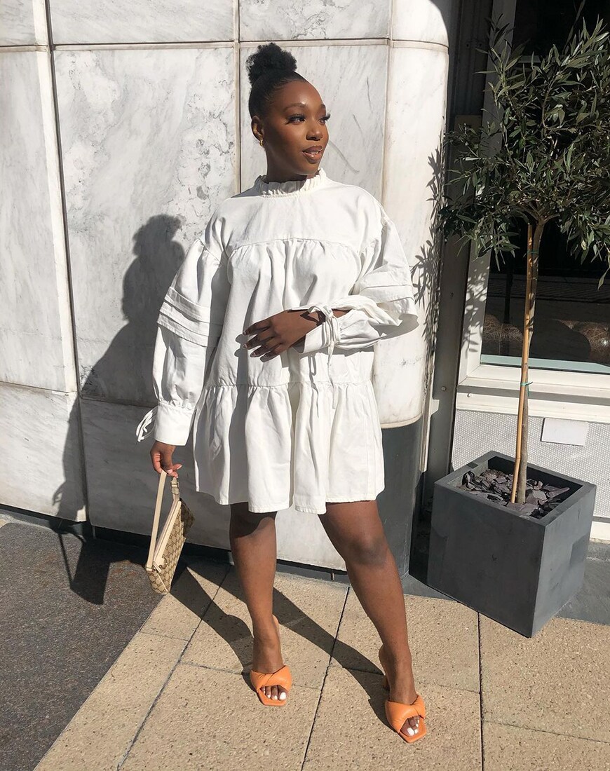 A woman wearing an off-white smock mini dress beside a small tree | ASOS Style Feed