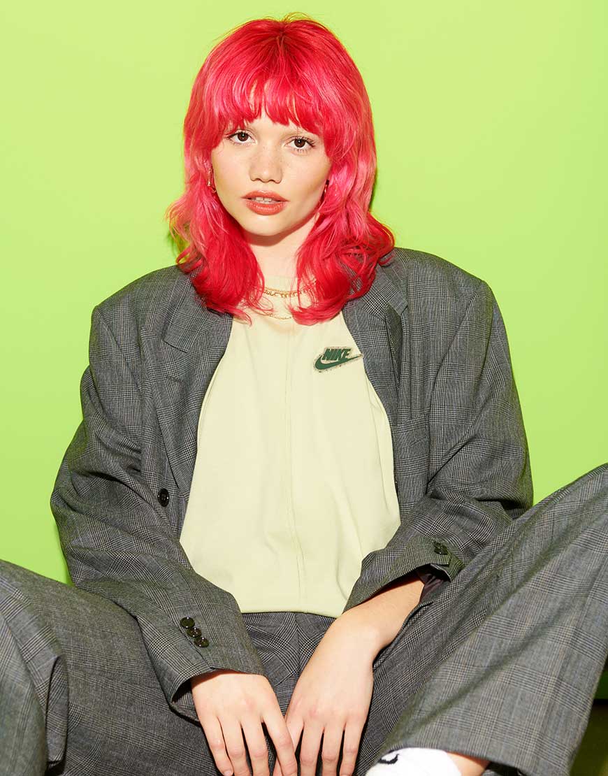 Florence, a woman with red hair, wears a grey pant suit and a lime green Nike branded t-shirt | ASOS Style Feed