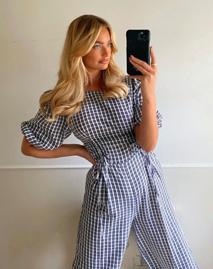 A woman with blonde hair taking a mirror selfie in a black and white gingham jumpsuit | ASOS Style Feed