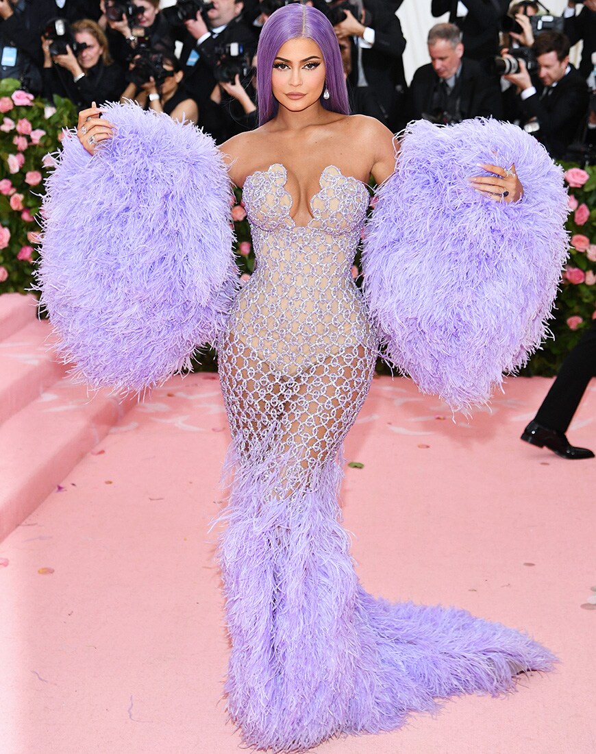 Kylie Kenner on a red carpet in a purple beaded gown with huge purple feather sleeves and purple hair | ASOS Style Feed