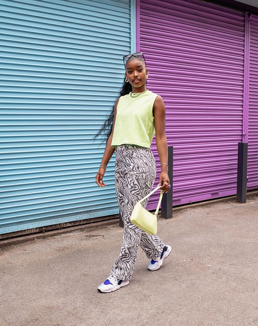 A woman wearing a neon-green top, swirl-print trousers and Nike Air Hurache trainers | ASOS Style Feed