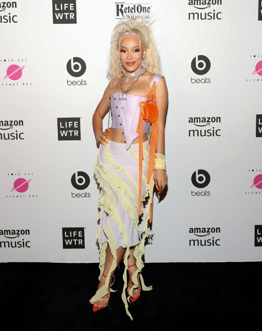 Doja Cat wears a pale pink corset with a tight pale pink silky skirt covered in lime green accents. | ASOS Style Feed