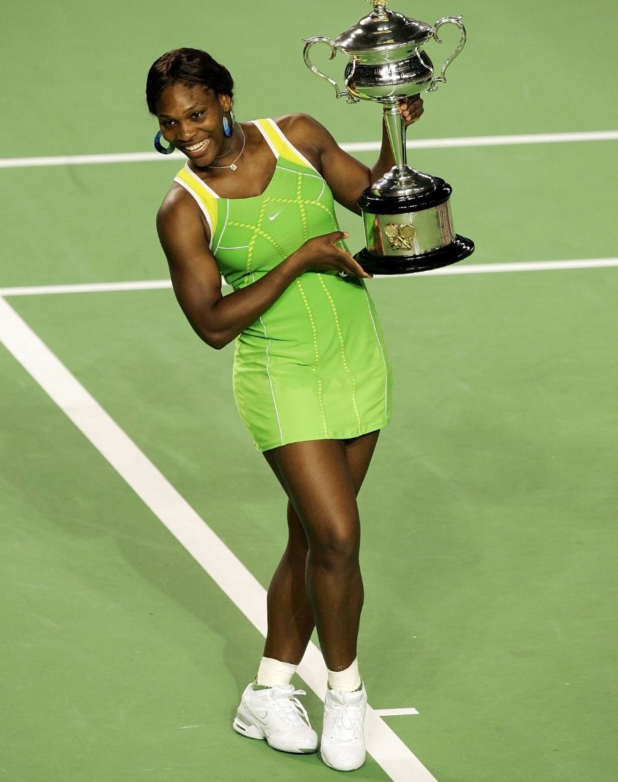 Serena Williams hold a trophy while wearing a green Nike tennis dress. | ASOS Style Feed