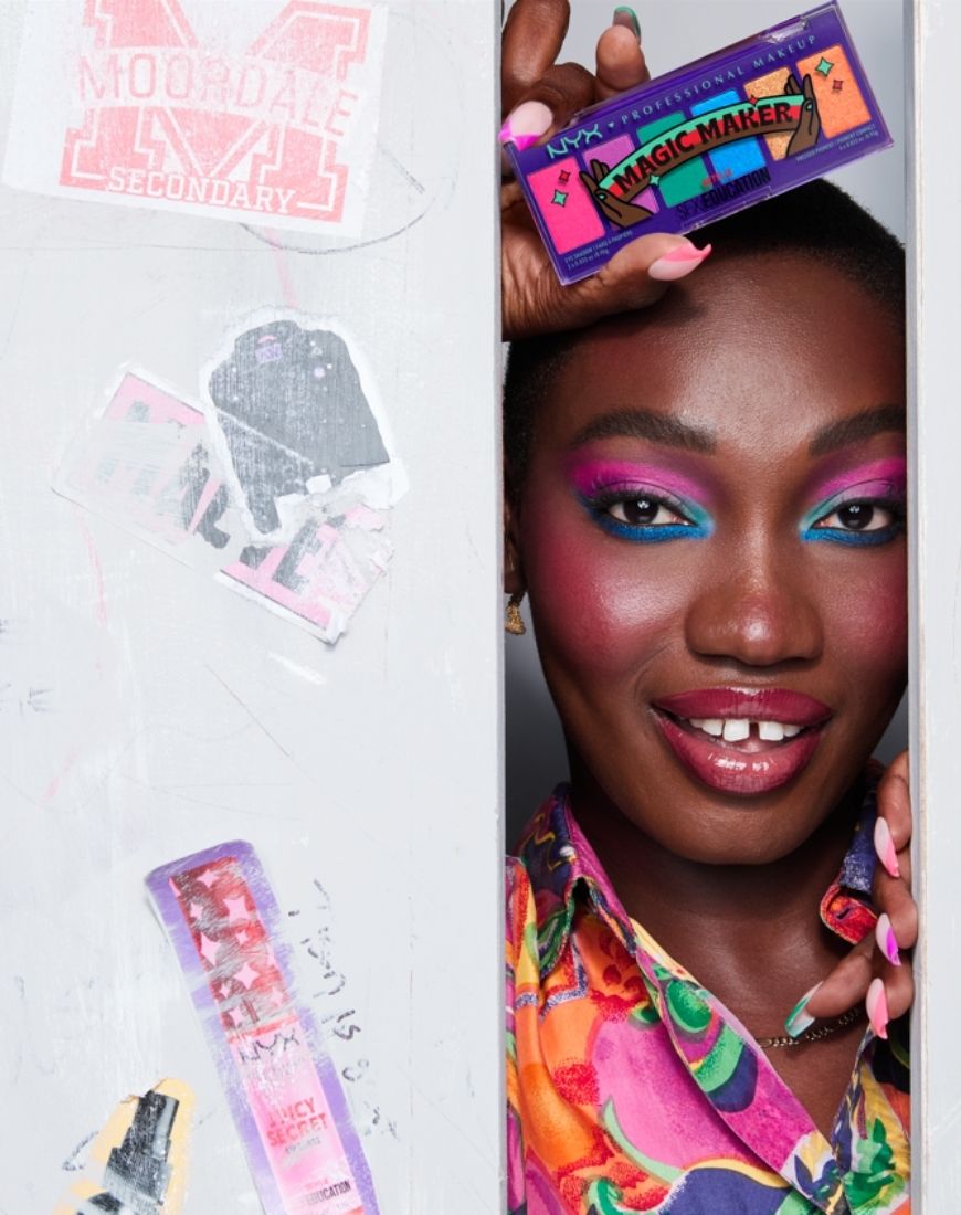 Picture of a model wearing bright, bold eyeshadows and holding the Magic Maker eyeshadow palette from NYX x Netflix. | ASOS Style Feed
